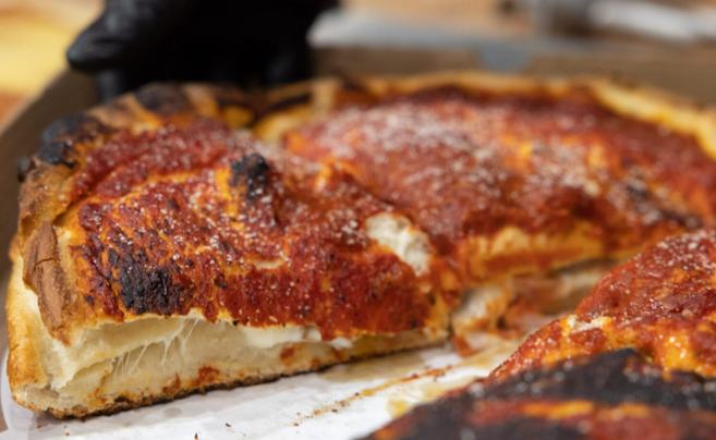 A slice of Chicago-style deep dish pizza with a thick crust at Big Poppa's Pizza