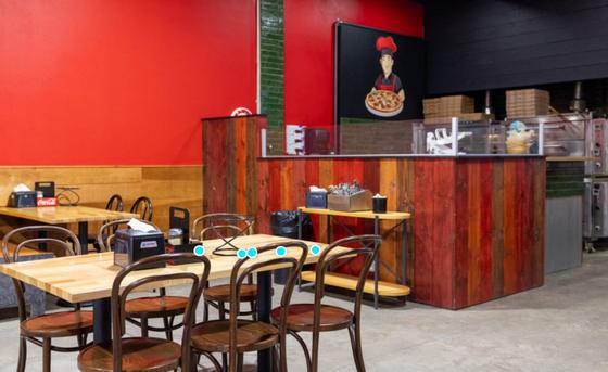 Dining area with wooden tables and a red accent wall at Big Poppa's Pizza in Sioux Falls