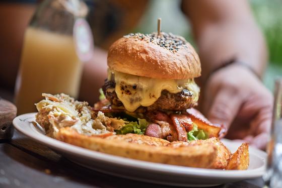 A stacked cheeseburger served on a plate with fries