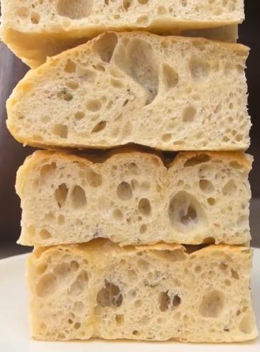 A stack of thick focaccia slices showing an airy, open crumb at North End Bakery & Deli