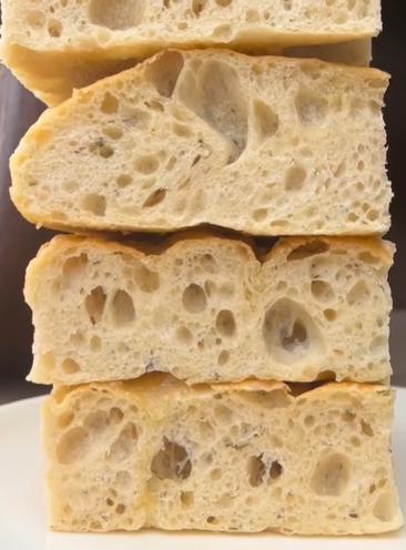 A stack of thick focaccia slices showing an airy, open crumb at North End Bakery &amp; Deli