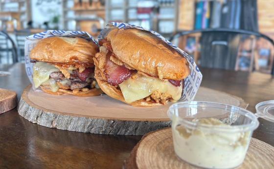 Two wrapped burgers on a wooden board with a cup of sauce at Ranch &amp; Roost in Sioux Falls