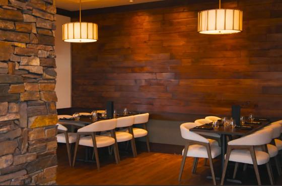 Dining room at Rivage Oak Kitchen in Sioux Falls with a stone pillar, dark wood tables and bar seating