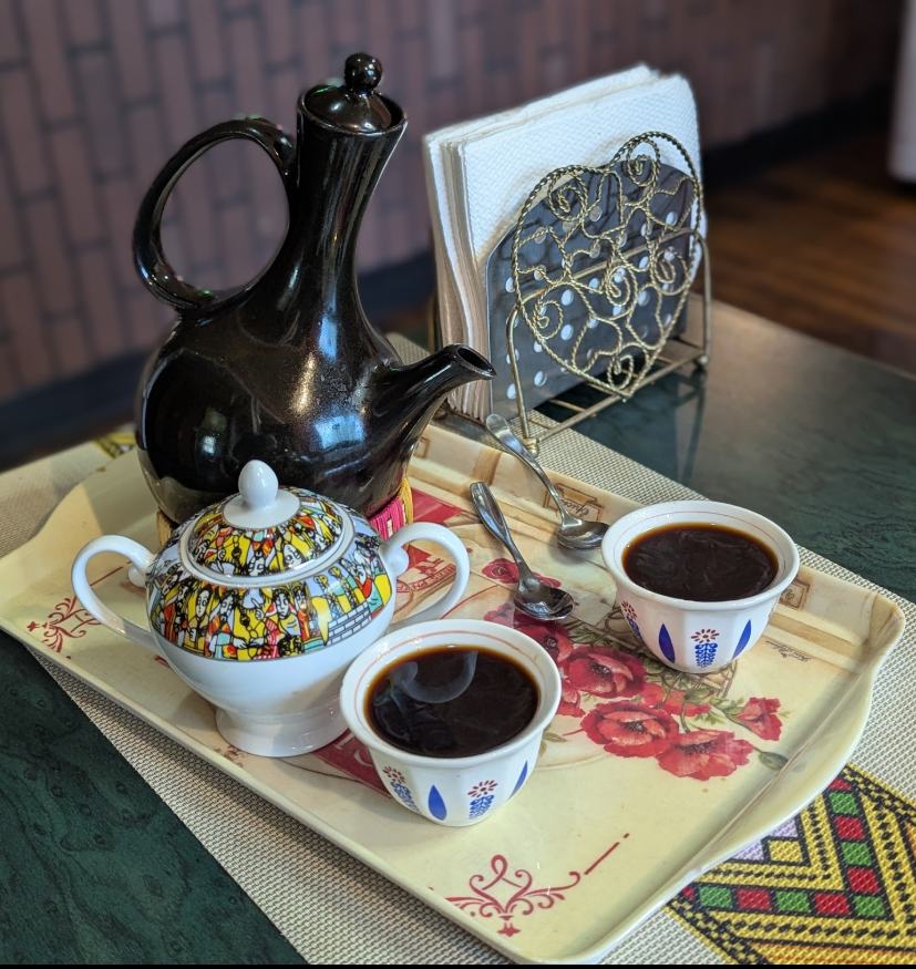 An Ethiopian coffee pot and small cups on a decorated tray at Shalom Coffee House