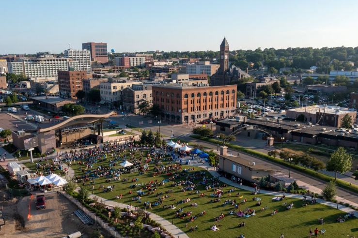 Aerial view of downtown Sioux Falls, South Dakota, with a green park and a crowd gathered in the foreground