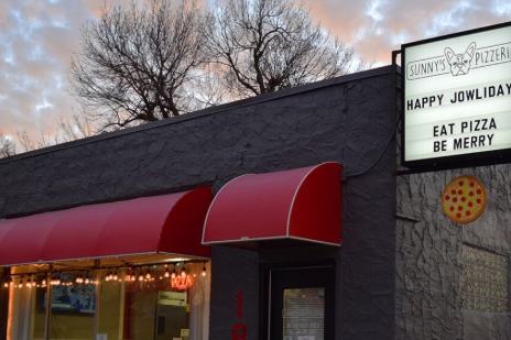 Storefront of Sunny's Pizzeria in Sioux Falls with red awnings and a marquee sign