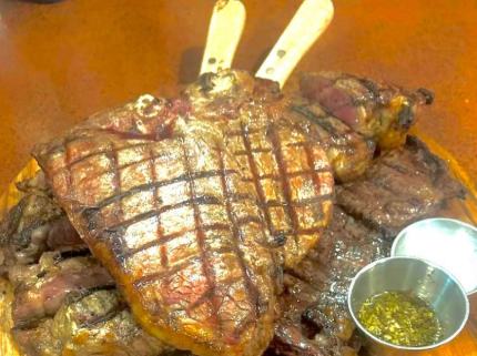 A grilled porterhouse steak with a small dish of green sauce at Tarquin Argentinian Restaurant