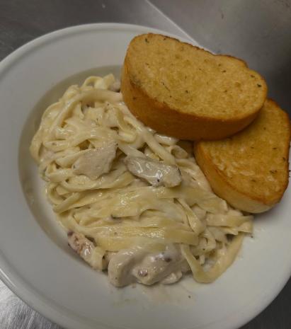 A plate of creamy fettuccine with two slices of garlic bread at Tomecelli's Pizza &amp; Pasta