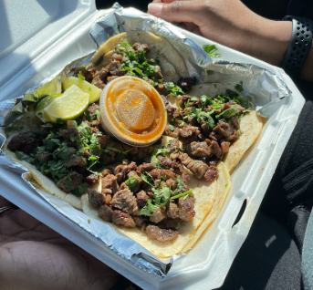 Tacos with steak, cilantro and a lime wedge in a takeout container at Tortilleria Hernandez
