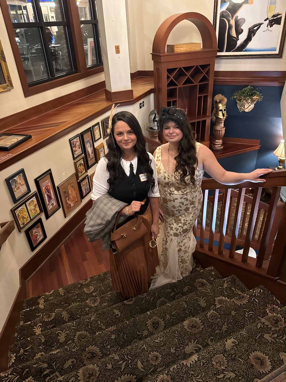 Two guests in vintage-style outfits smiling on a staircase at Minervas