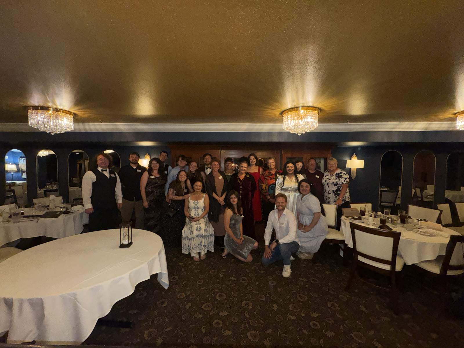 A large group of costumed dinner guests posing together